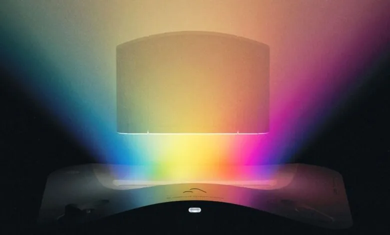 A retro computer monitor and base illuminated by a rainbow spectrum of light.