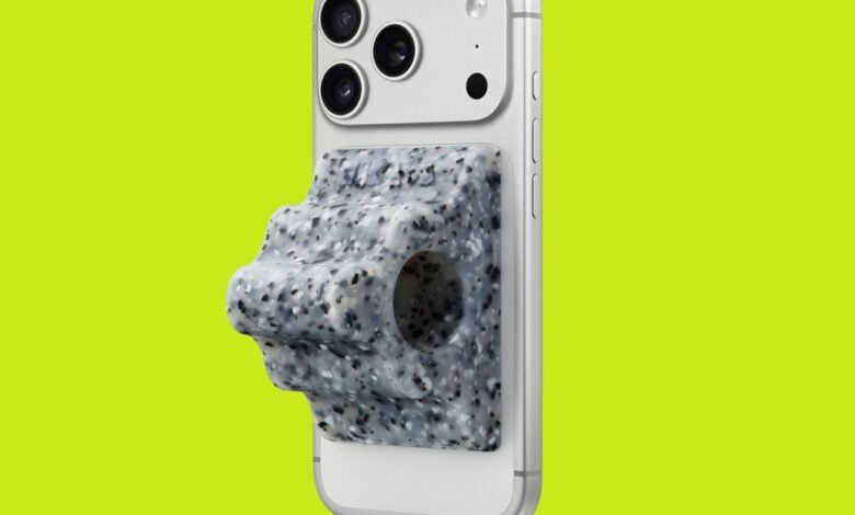 Close-up of a speckled gray phone grip stand attached to a silver iPhone.