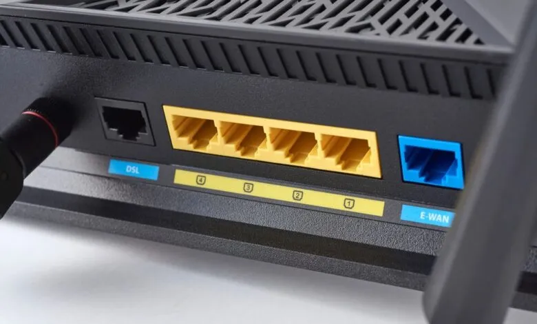 Close-up of a black ASUS router's rear ports, showing DSL, Ethernet LAN, and E-WAN connections.