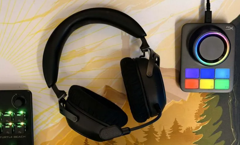 Black gaming headset and audio control devices on a desk mat with a sunrise and forest design.