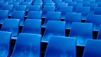 Rows of empty blue stadium seats viewed from a low angle.
