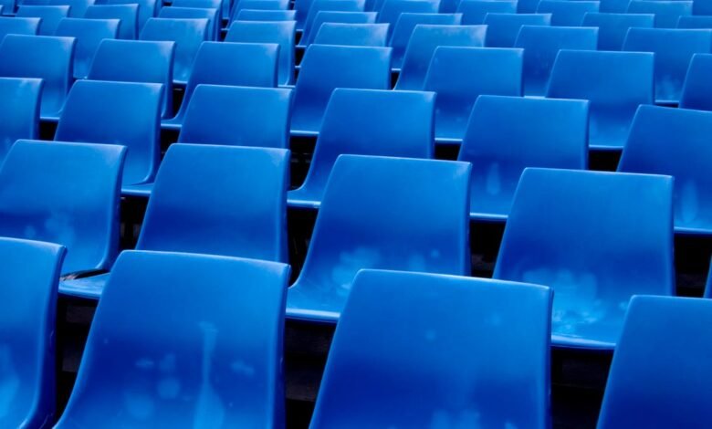 Rows of empty blue stadium seats viewed from a low angle.