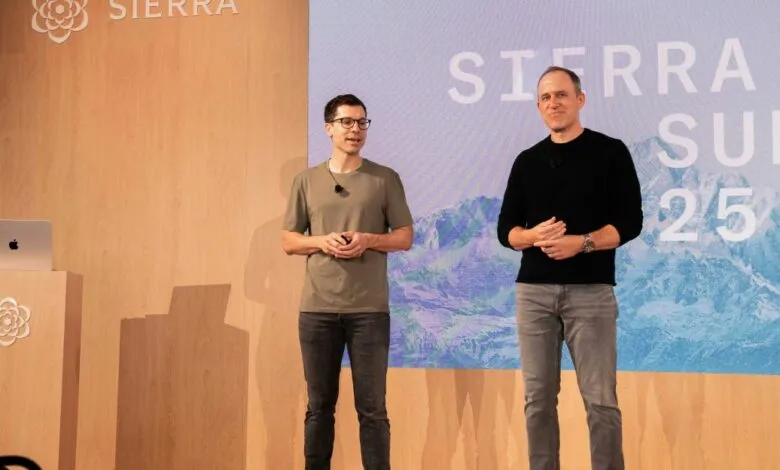 Two men stand on a stage in front of a screen displaying 'SIERRA SUMMIT 25' and a mountain landscape.