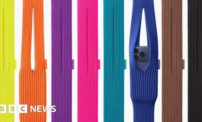 A collection of colorful knitted phone sleeves, one holding a smartphone.