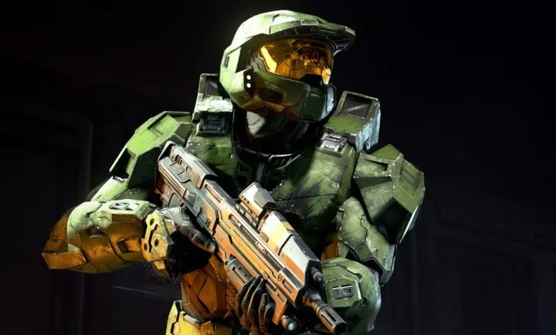 Master Chief in green armor holding a futuristic rifle, looking to the side.