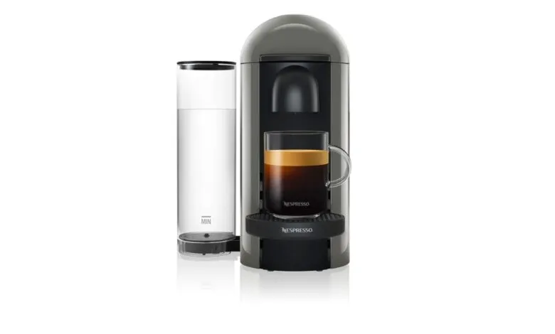 Gray Nespresso VertuoPlus coffee maker with glass mug.