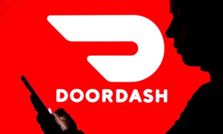 Silhouette of a person using a smartphone with the DoorDash logo in the background.