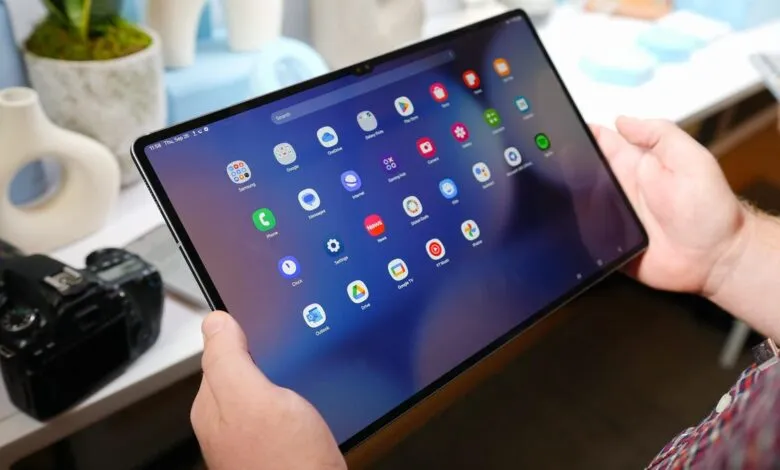 Hands holding a tablet displaying app icons on a blue background.