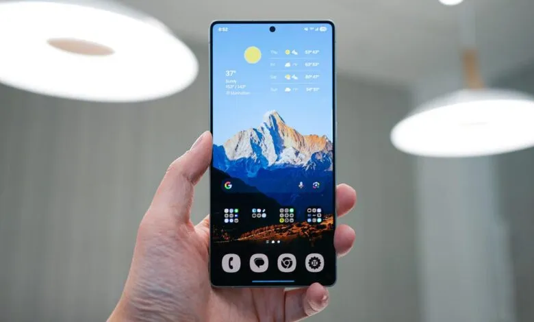 Hand holding smartphone displaying weather app and mountain wallpaper.