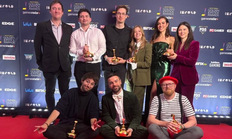 Group of people posing with Golden Joystick Awards trophies on a red carpet.