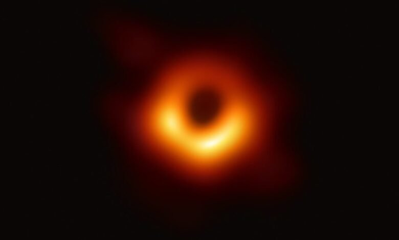 The first image of a black hole, showing a bright orange ring around a dark center.