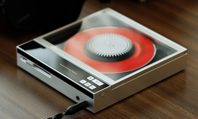 A portable CD player with a red disc inside, resting on a wooden surface.