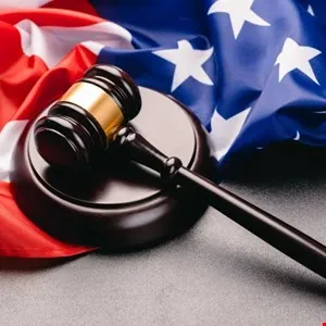 A wooden gavel rests on a sound block against a backdrop of the American flag.