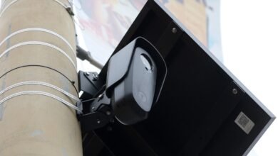 Close-up of a black surveillance camera mounted on a pole with a solar panel.