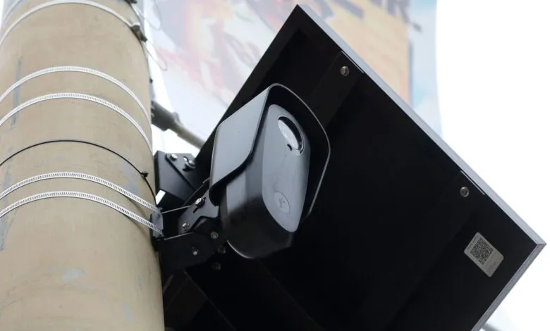 Close-up of a black surveillance camera mounted on a pole with a solar panel.