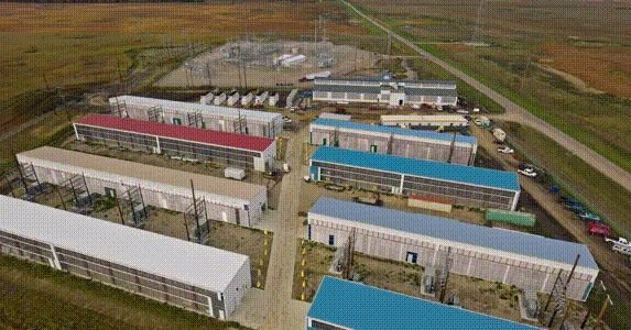 Aerial view of a large industrial facility with multiple long, rectangular buildings and a substation.