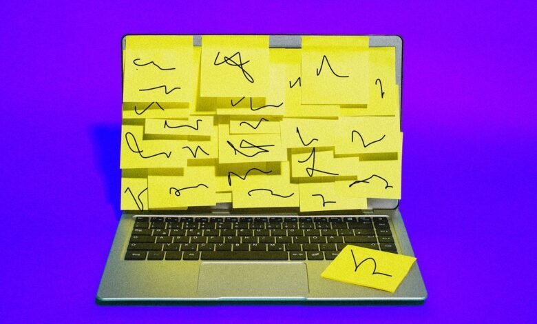 Laptop screen covered in yellow sticky notes with handwritten scribbles.