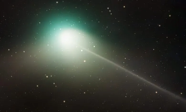A bright comet with a glowing tail streaks across a dark, star-filled sky.