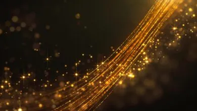 Golden shimmering particles and light trails against a dark background.