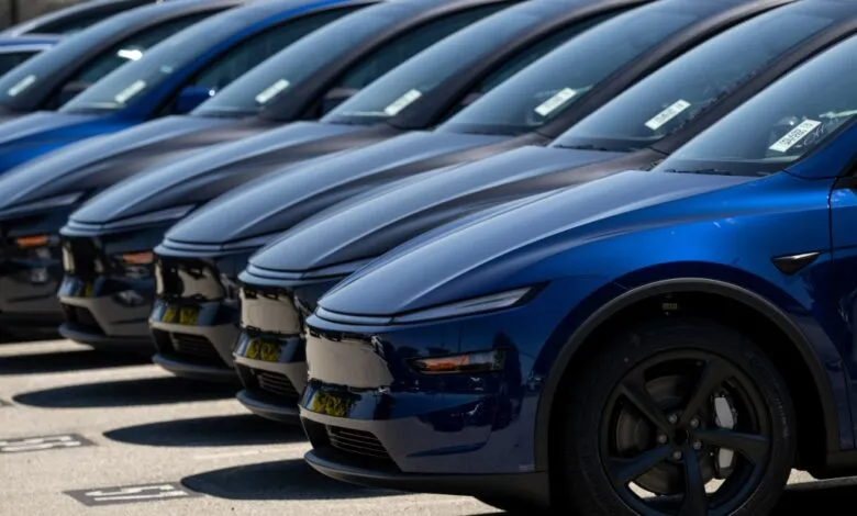 A line of new blue and dark gray electric cars parked in a lot.
