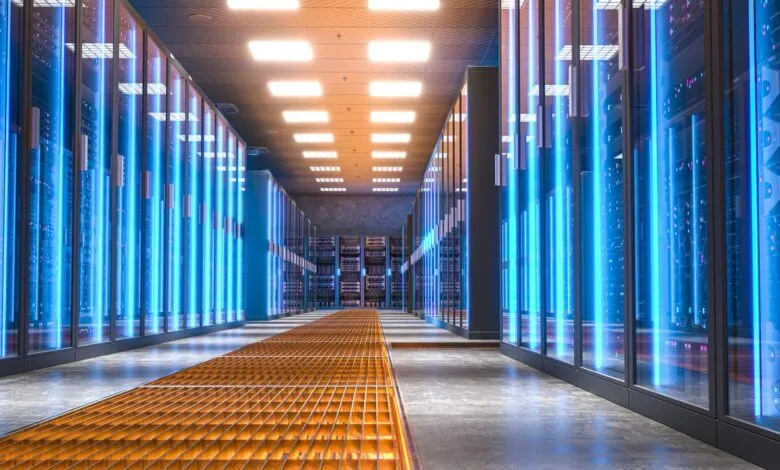 A futuristic data center aisle with rows of servers illuminated by blue LED lights.