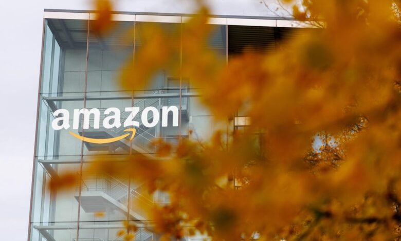 Amazon logo on a modern glass building facade with autumn leaves in the foreground.