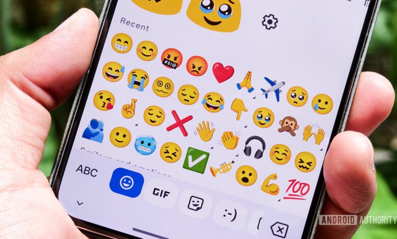 Close-up of a person's thumb scrolling through the Gboard emoji keyboard on a smartphone.