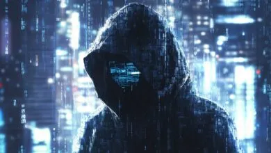 A hooded figure with a digital face displaying code, set against a blurred city background.