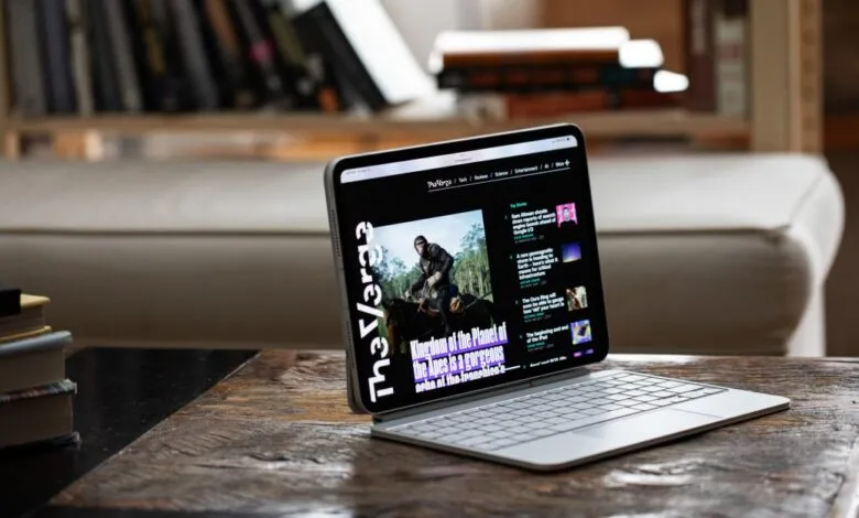 A modern tablet with a keyboard stand displays The Verge website.