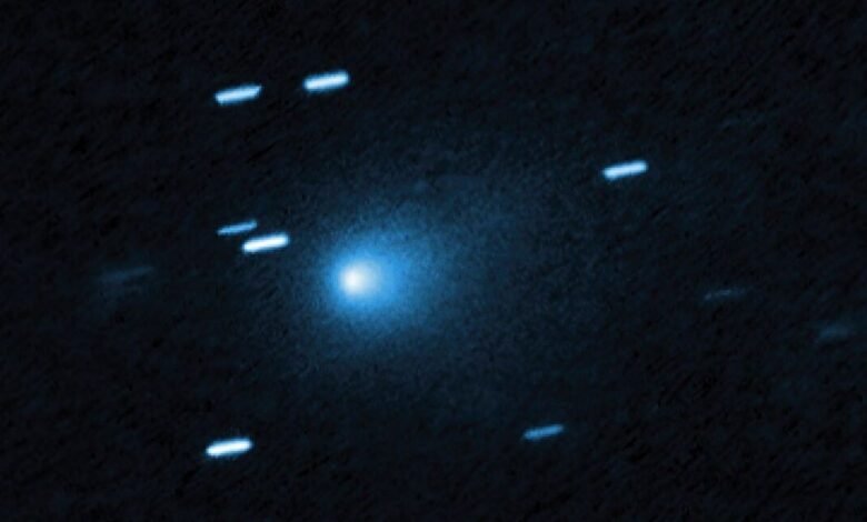 A bright blue comet with a glowing nucleus against a dark, star-filled sky.