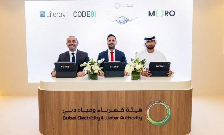 Three men in suits and traditional attire seated at a table with tablets, in front of a screen displaying logos.