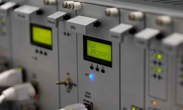 Close-up of a rackmount industrial control system with illuminated displays and status lights.
