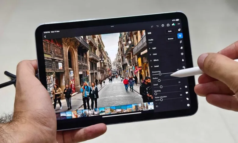 Hands holding iPad Mini editing street scene photo with Apple Pencil.