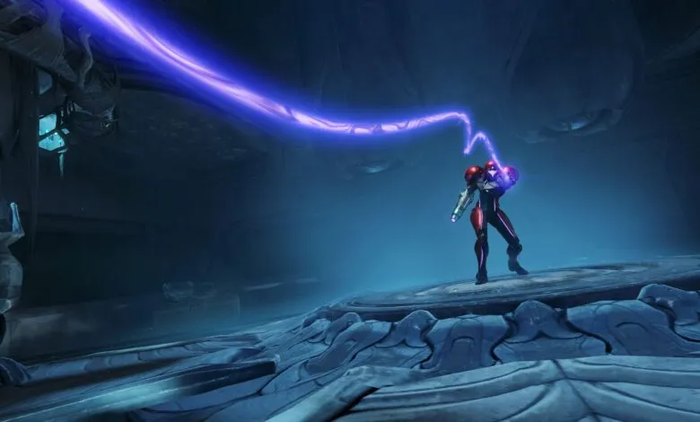 Samus Aran in her power suit firing a purple energy beam in a dark, alien environment.