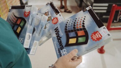 Person holding multiple boxes of Microsoft Windows 95 software.