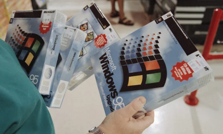Person holding multiple boxes of Microsoft Windows 95 software.