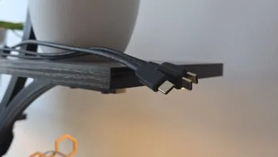 Close-up of two braided USB-C cables with black connectors resting on a wooden shelf.