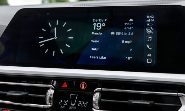 Close-up of a car's digital dashboard displaying time, weather, and vehicle icons.