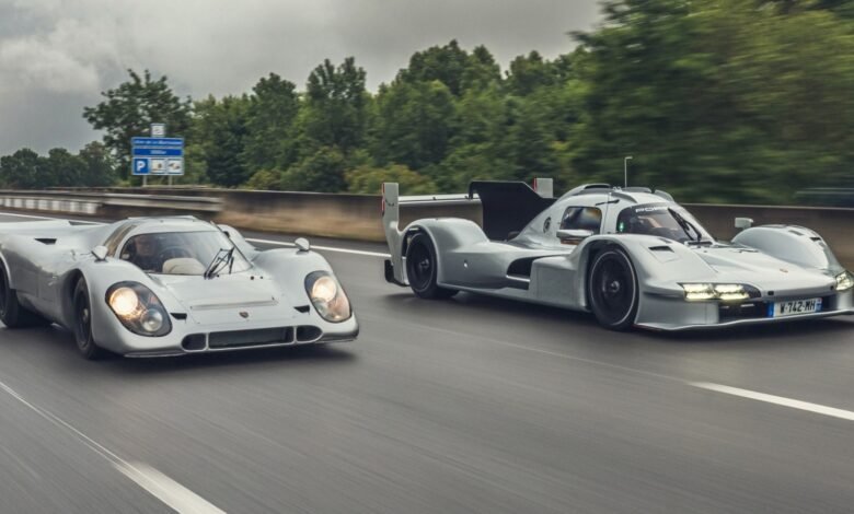 Two silver Porsche race cars driving on a highway, one classic and one modern.