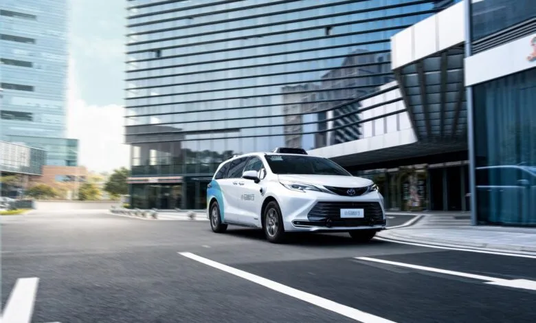 Pony.ai robotaxi driving on city street with modern buildings in background.