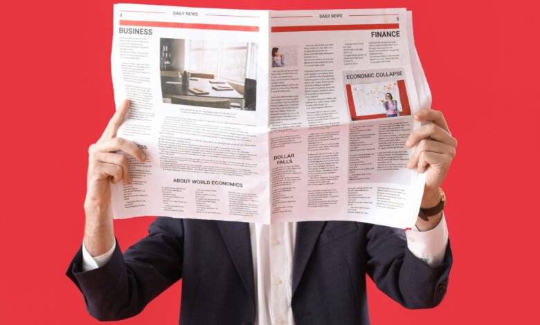 Person in suit reading newspaper with business and finance headlines.