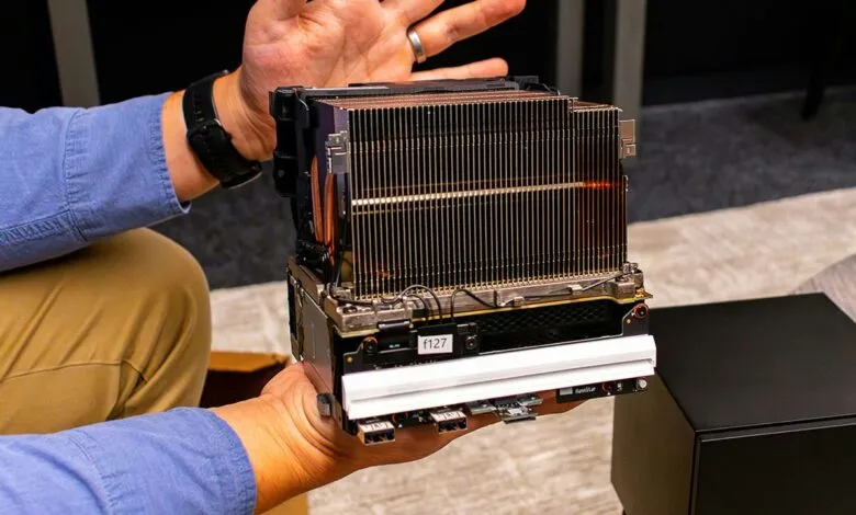 Hands hold a complex computer component with heatsink and ports.