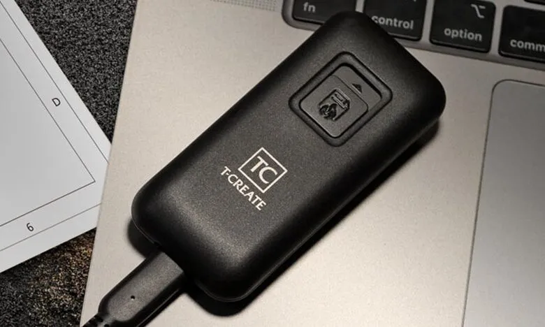 Black T-CREATE portable SSD connected to a laptop keyboard.