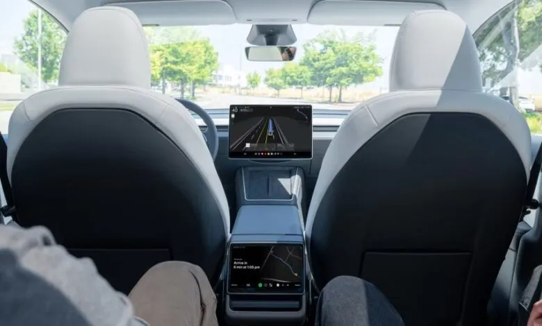 Interior view of a futuristic car with white and black seats and large touchscreens.