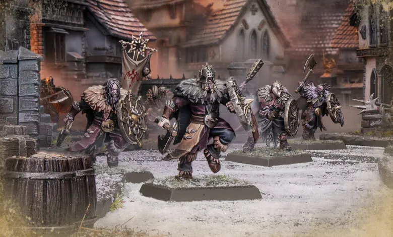 Miniature fantasy warriors in armor with shields and weapons, standing in a snowy village.