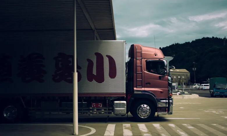 Side profile of a rose gold Hino truck with Japanese characters on its trailer.