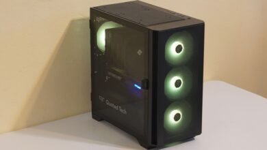 A black computer tower with a glass side panel and illuminated green fans.