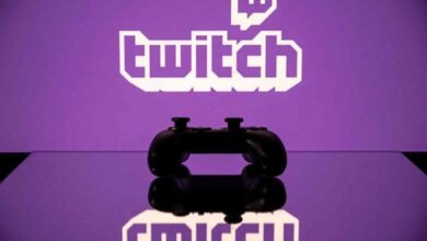 Game controller reflects Twitch logo on a purple surface.