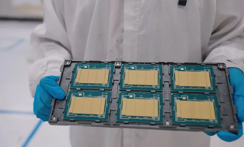 Technician holds tray of microchips in cleanroom environment.