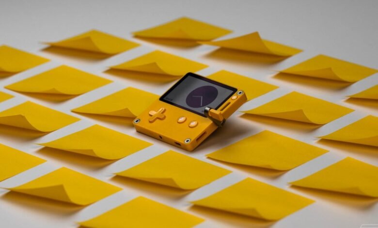A bright yellow handheld gaming device surrounded by yellow sticky notes.
